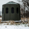 Image of Green blind in a snowy field with trees in the background