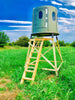 Image of Green blind on a wooden ladder in a grassy field with a blue sky.